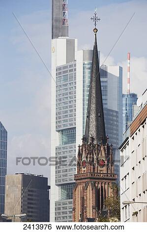 Old church steeple against the background of newer skyscrapers with blue sky and clouds; Frankfurt am Main, Germany View Large Photo Image Stock Photograph - Old church steeple against the background of newer skyscrapers with blue sky and clouds; Frankfurt am Main, Germany. Fotosearch