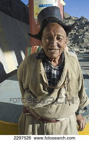 Stock Photograph - Old Ladakhi man at the entrance to Leh. Leh was the capital of the Himalayan kingdom of Ladakh, now the Leh District in the state of Jammu and Kashmir, India. Leh is at an altitude of 3, 500 meters (11, 483 ft).. Fotosearch