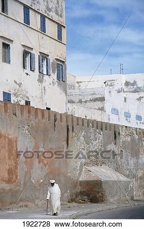 Stock Photo - Old Local Man Walking Down The Street. Fotosearch
