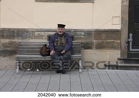Stock Image - Old Man Sitting On A Bench, Bamberg, Bavaria, Germany. Fotosearch
