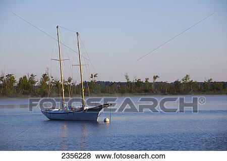 Stock Photo - Old Sailboat In Early Morning Light On Brome Lake; Knowlton, Quebec, Canada. Fotosearch