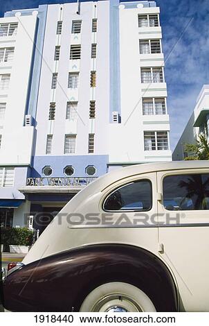 Stock Image - Old White Car, Art Deco Building. Fotosearch