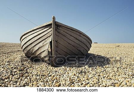 Stock Image - Old Wooden Boat On Pebbled Beach. Fotosearch