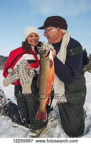 Older fisherman and younger woman showing off a large splake they caught ice fishing; Ontario, Canada View Large Photo Image Stock Photo - Older fisherman and younger woman showing off a large splake they caught ice fishing; Ontario, Canada. Fotosearch