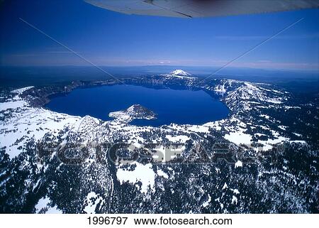 Stock Photo - Oregon, Crater Lake, Aerial Overview, Snow Scattered, Clear Blue Sky Background A51H. Fotosearch