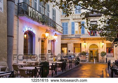 Stock Photography - Outdoor patio seating on an illuminated street at dusk; Arles, Provence-Alpes-Cote D'Azur, Bouches-Du-Rhone, France. Fotosearch