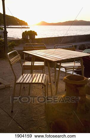 Stock Photo - Outdoor Table And Chairs On Waterfront At Sunset, Lopud, Croatia. Fotosearch