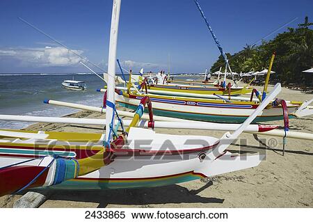 Stock Photography - Outrigger canoes await passengers on Sanur Beach; Bali, Indonesia. Fotosearch