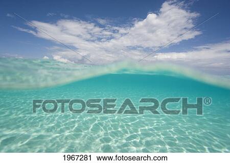 Stock Image - Over/Under View Of Shallow Ocean Water And Sky Above.. Fotosearch