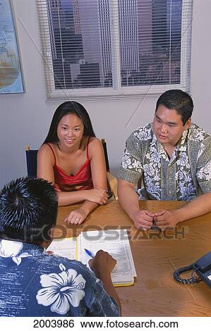 Stock Photograph - Overview Of Young Local Couple Meeting With Bank Loan Officer, Office Setting. Fotosearch