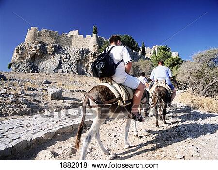Stock Photo - Overweight Tourists On The Backs Of Donkeys On The Path To The Acropolis Of Lindos. Fotosearch