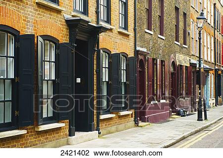 Stock Image - Painted open shutters on windows of brick buildings, Spitalfields; London, England. Fotosearch