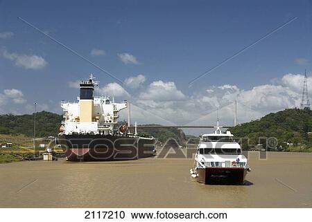 Stock Image - Panama, Panama Canal, cruise boat coming into Pedro Miguel Lock, new Millennium Bridge with waiting ship. Fotosearch