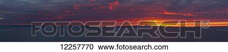 Stock Image - Panorama of red clouds over Bristol Bay at sunrise in summer, Walrus Islands State Game Sanctuary, Round Island, Bristol Bay, Western Alaska, USA. Fotosearch