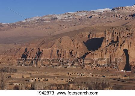 Stock Image - Panoramic View Of Bamiyan And The Escarpment With Hundreds Of Caves And The Niche That Contained The Large Buddha Statue Destroyed By The Taliban In 2001, Bamian Province, Afghanistan. Fotosearch