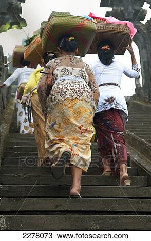 Stock Image - Parade in a ceremony with women carrying offerings on their head; Bali. Fotosearch