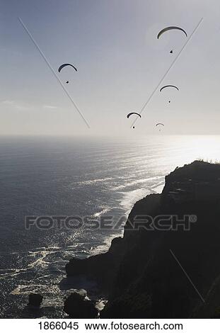 Stock Photography - Paragliders Soar Free Over The Cliffs Of The Bukit Peninsula In Bali, Indonesia. Fotosearch