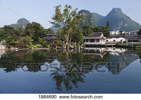 Stock Image - Park Along The Water's Edge Reflected In The Water; Yangshuo, Guangxi, China. Fotosearch