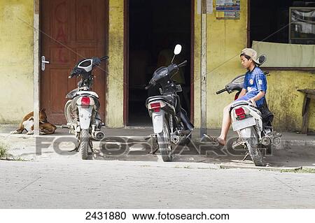 Stock Image - Parked motorcycles and boy, Dokan, North Sumatra, Indonesia. Fotosearch