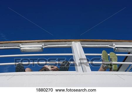 Passengers On Board Cruise Ship Reading With Their Feet Up On The Railings View Large Photo Image Stock Image - Passengers On Board Cruise Ship Reading With Their Feet Up On The Railings. Fotosearch