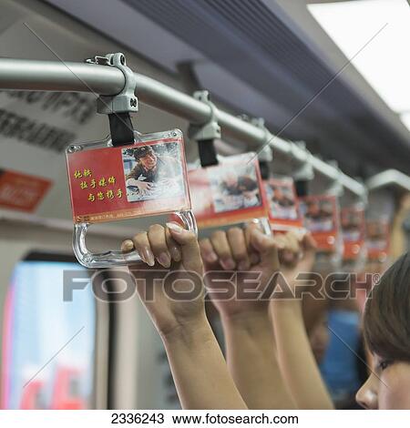 Stock Image - Passengers On Public Transportation Hold Onto Handles While Riding; Beijing, China. Fotosearch