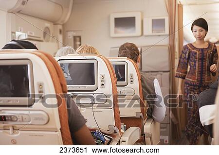 Passengers seated aboard an airplane and a flight attendant in the aisle; Singapore View Large Photo Image Stock Image - Passengers seated aboard an airplane and a flight attendant in the aisle; Singapore. Fotosearch
