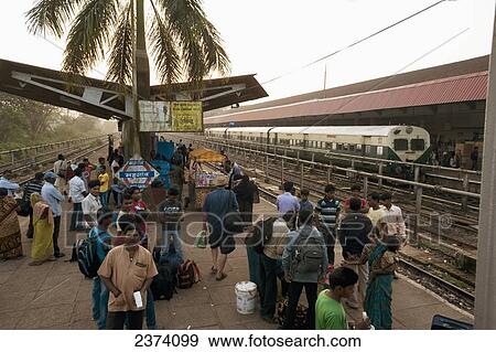 Passengers wait on the platform of a train station for arriving trains; India View Large Photo Image Stock Photo - Passengers wait on the platform of a train station for arriving trains; India. Fotosearch