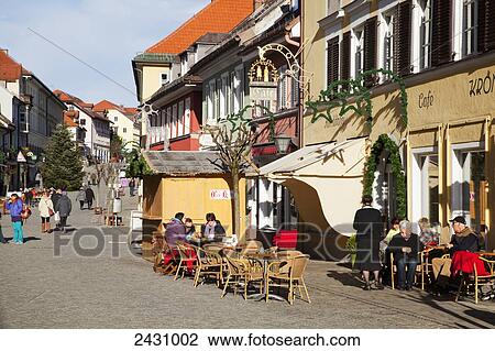 Stock Image - Patio seating and pedestrians along a street; Murnau, Bavaria, Germany. Fotosearch