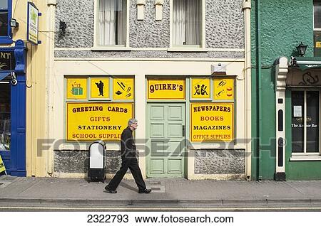 Stock Image - Pedestrian passing by old shop; Cahersiveen, Iveragh Peninsula, County Kerry, Ireland, UK. Fotosearch