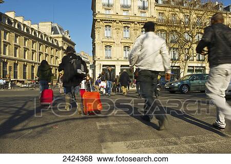 Pedestrians crossing a street at an intersection, some of them rolling luggage behind them; Paris, France View Large Photo Image Stock Photo - Pedestrians crossing a street at an intersection, some of them rolling luggage behind them; Paris, France. Fotosearch