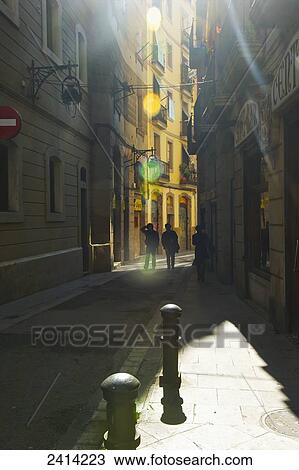 Stock Image - Pedestrians on a narrow walkway between buildings; Barcelona, Spain. Fotosearch