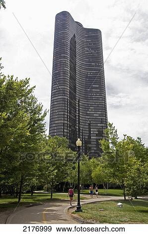 Stock Photo - Pedestrians On A Path In An Urban Park With A Tall Building; Chicago Illinois United States Of America. Fotosearch