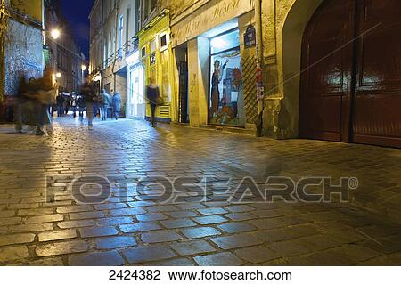 Pedestrians on a walkway outside retail buildings at nighttime; Paris, France View Large Photo Image Stock Image - Pedestrians on a walkway outside retail buildings at nighttime; Paris, France. Fotosearch