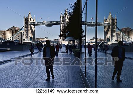 Stock Photo - Pedestrians on a walkway with London's tower bridge in the background; London, England. Fotosearch