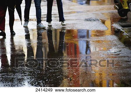 Pedestrians on a wet walkway with puddles reflecting the colourful buildings; Barcelona, Spain View Large Photo Image Stock Photo - Pedestrians on a wet walkway with puddles reflecting the colourful buildings; Barcelona, Spain. Fotosearch