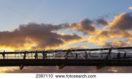 Stock Image - Pedestrians on Millenium Bridge at sunset; London, England. Fotosearch