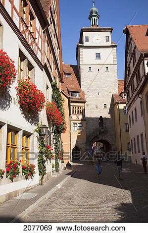 Pedestrians Walking Down A Narrow Street In Between Buildings; Rothenburg Ob Der Tauber Bavaria Germany View Large Photo Image Stock Photo - Pedestrians Walking Down A Narrow Street In Between Buildings; Rothenburg Ob Der Tauber Bavaria Germany. Fotosearch