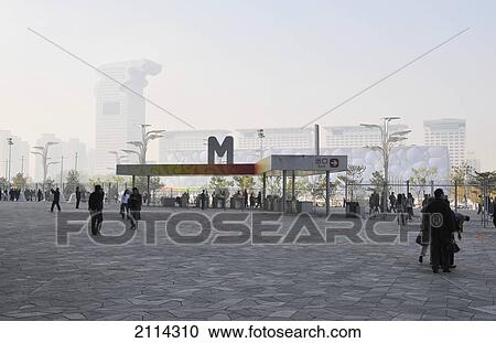 Stock Image - Pedestrians Walking In A Town Square With Smog Covering The Buildings In The Background; Beijing China. Fotosearch