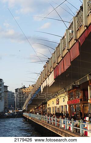 Stock Photograph - Pedestrian's Walking On A Promenade With Shops Along The Water's Edge; Istanbul Turkey. Fotosearch