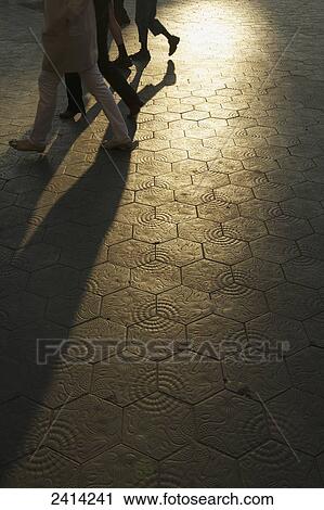 Stock Image - Pedestrians walking on an illuminated path with decorative blocks; Barcelona, Spain. Fotosearch