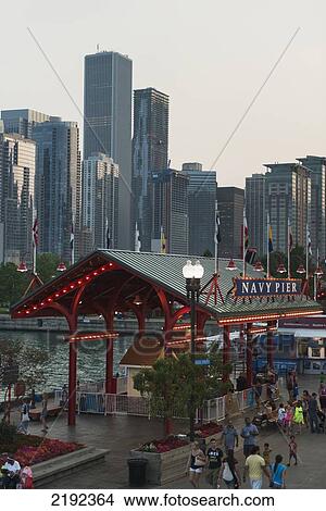 Pedestrians Walking On The Promenade At Navy Pier With Skyscrapers In The Background; Chicago Illinois United States Of America View Large Photo Image Picture - Pedestrians Walking On The Promenade At Navy Pier With Skyscrapers In The Background; Chicago Illinois United States Of America. Fotosearch
