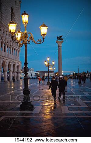 Stock Image - Pedestrians Walking On The Promenade At Dusk On A Rainy Day; Venice Venezia Italy. Fotosearch