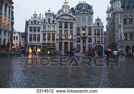 Stock Image - Pedestrians walking through a wet town square; Brussels, Belgium. Fotosearch