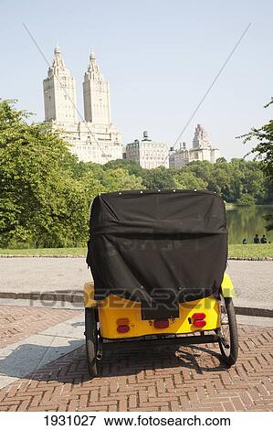Stock Photo - Pedicab Overlooking Water In Central Park With Skyline, New York, Usa; New York, Usa. Fotosearch