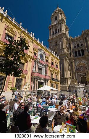 Stock Image - People At Cafe Tables In Square In Front Of Cathedral And Palacio Episcopal, Malaga, Andalucia, Spain. Fotosearch