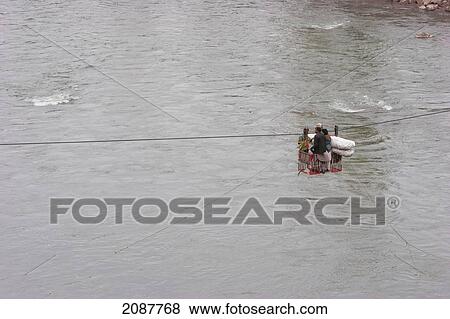 Stock Photo - People Carrying Bails On A Ropeway Over The Jhelum River After The 8 October 2005 Earthquake, Subri, Azad Kashmir, Pakistan. Fotosearch