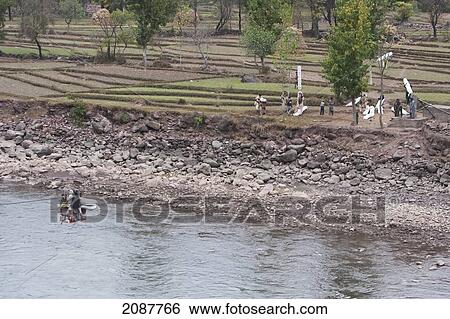 Stock Photograph - People Carrying Bails On A Ropeway Over The Jhelum River After The 8 October 2005 Earthquake, Subri, Azad Kashmir, Pakistan. Fotosearch