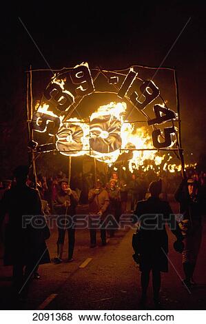 People Carrying Large Banner In Front Of 31 Burning Poppies On Bonfire Night To Commemorate The 31 Villagers Lost In The World Wars, East Hoathly, East Sussex, Uk View Large Photo Image Stock Photo - People Carrying Large Banner In Front Of 31 Burning Poppies On Bonfire Night To Commemorate The 31 Villagers Lost In The World Wars, East Hoathly, East Sussex, Uk. Fotosearch