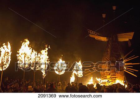 Stock Photo - People Carrying Large Banner In Front Of 31 Burning Poppies On Bonfire Night To Commemorate The 31 Villagers Lost In The World Wars, East Hoathly, East Sussex, Uk. Fotosearch