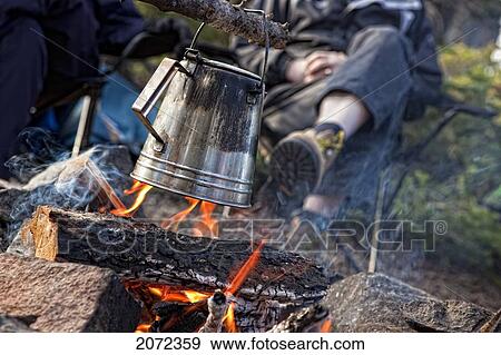 People Enjoying A Campfire While Making A Pot Of Boiling Water View Large Photo Image Stock Photo - People Enjoying A Campfire While Making A Pot Of Boiling Water. Fotosearch